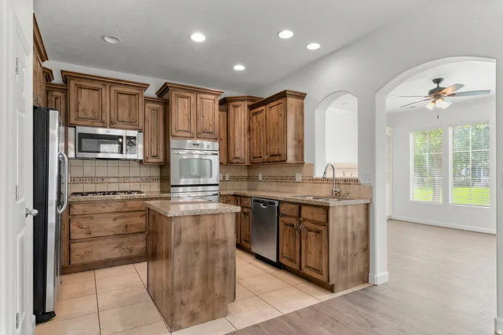 Kitchen featuring wood cabinetry, stainless steel appliances, a tiled backsplash, and recessed lighting