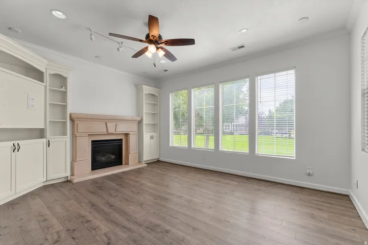 Wood-finish flooring with a fireplace featuring a light-toned surround
