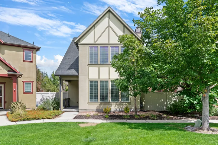 Two-story exterior with stucco and decorative trim, multi-pane windows, covered entry, and mature landscaping