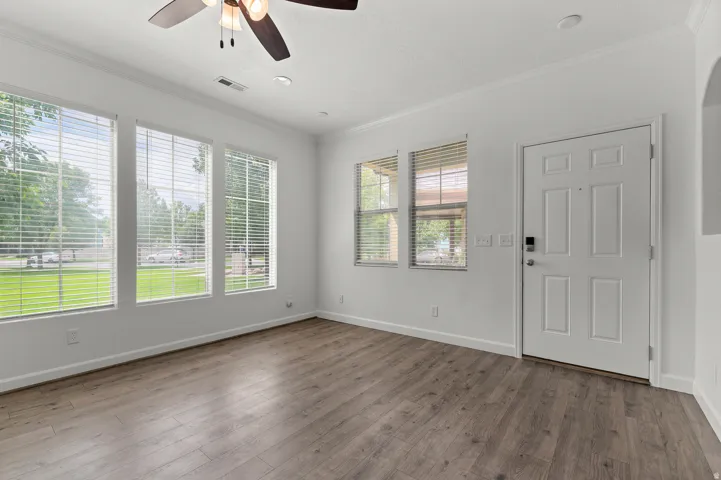 Wood-finish flooring, multiple windows with blinds, recessed lighting, ceiling fan, and a paneled entry door with smart lock