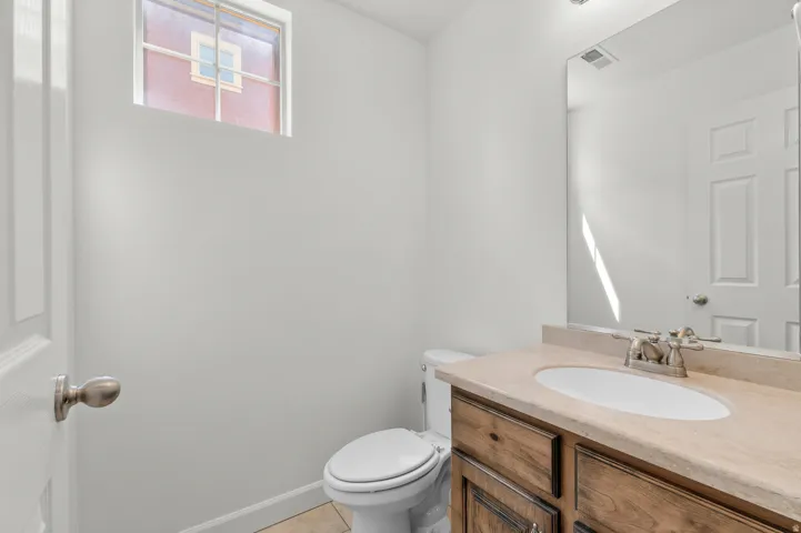 Powder room featuring a single vanity with a built-in sink, wood-finish cabinetry, and a framed mirror