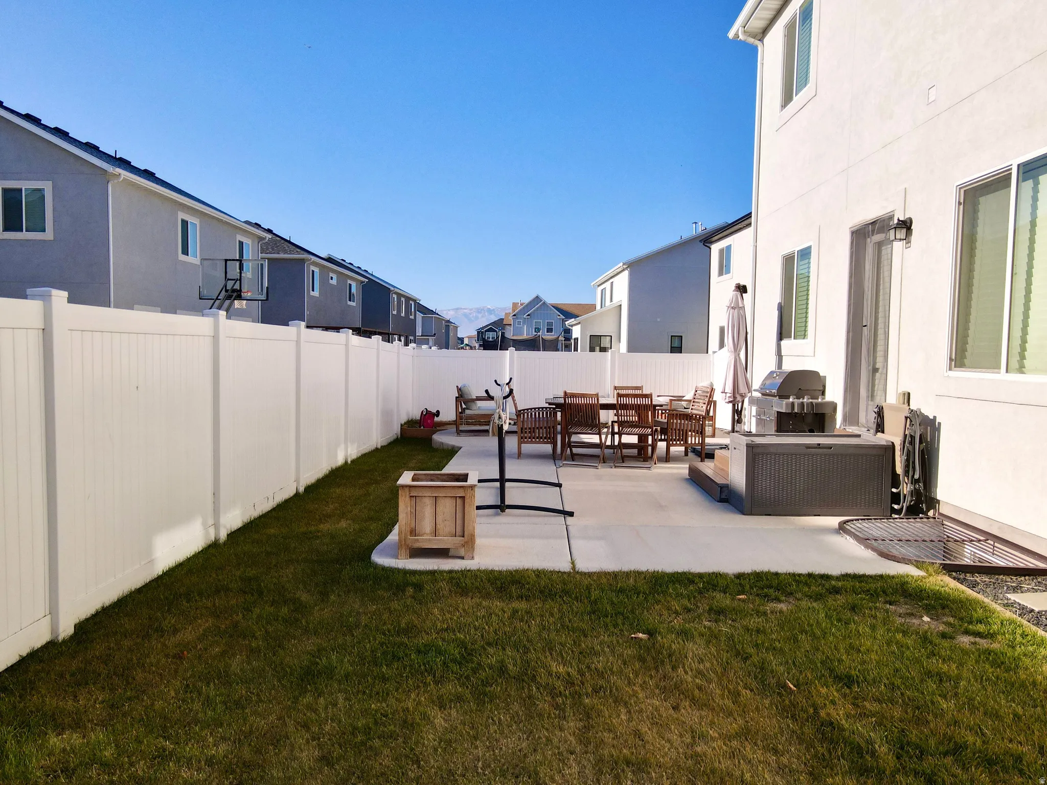Manicured lawn, concrete patio, white privacy fencing, and exterior wall lighting