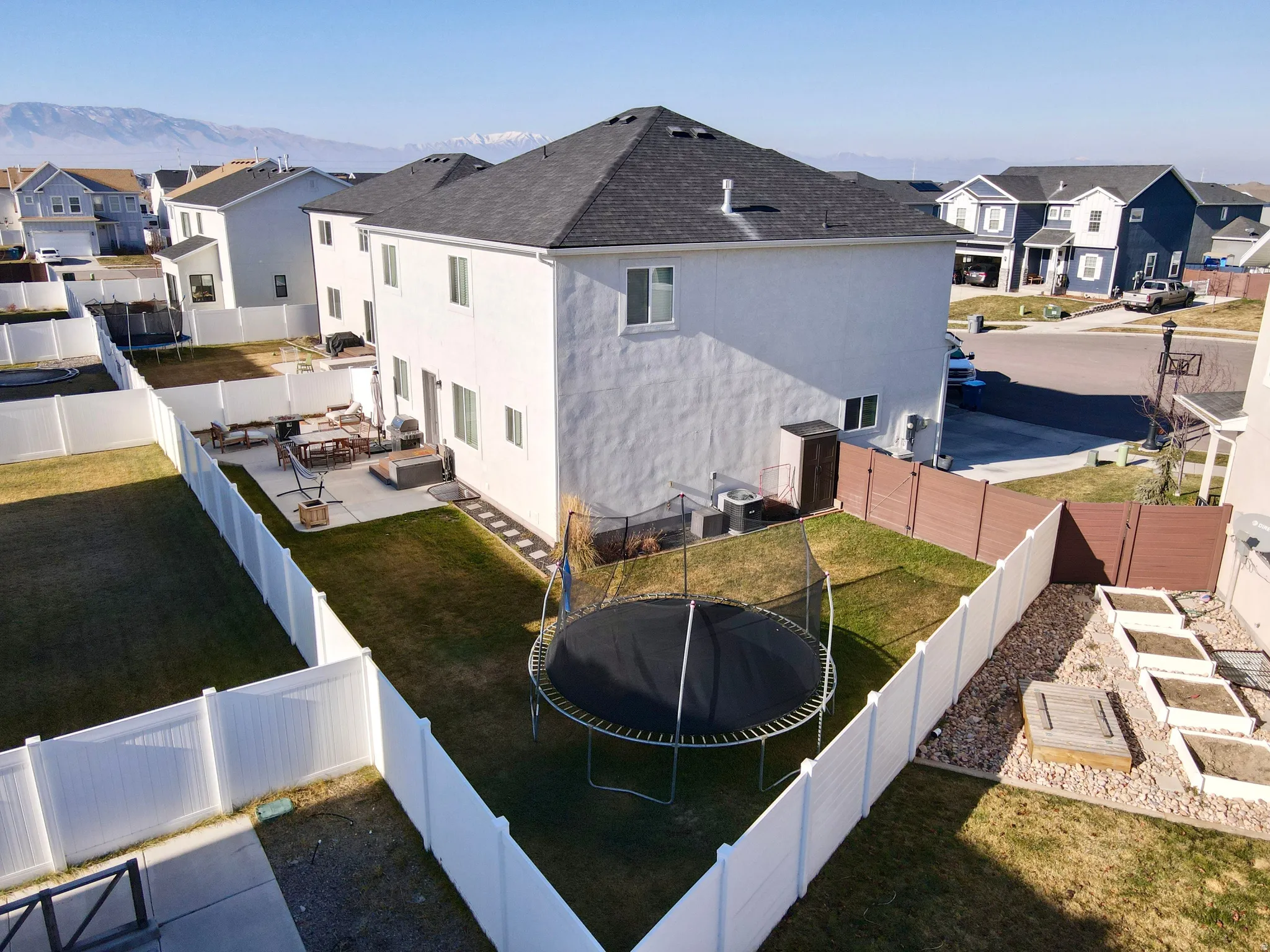 Expansive backyard oasis featuring a trampoline, manicured lawn, and white vinyl fencing