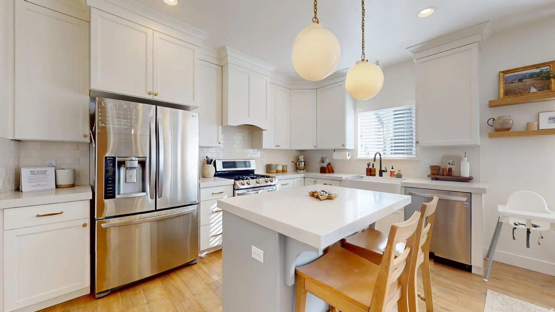 Kitchen featuring white cabinetry, stainless steel appliances, a center island with seating, a farmhouse sink, and wood-finish flooring