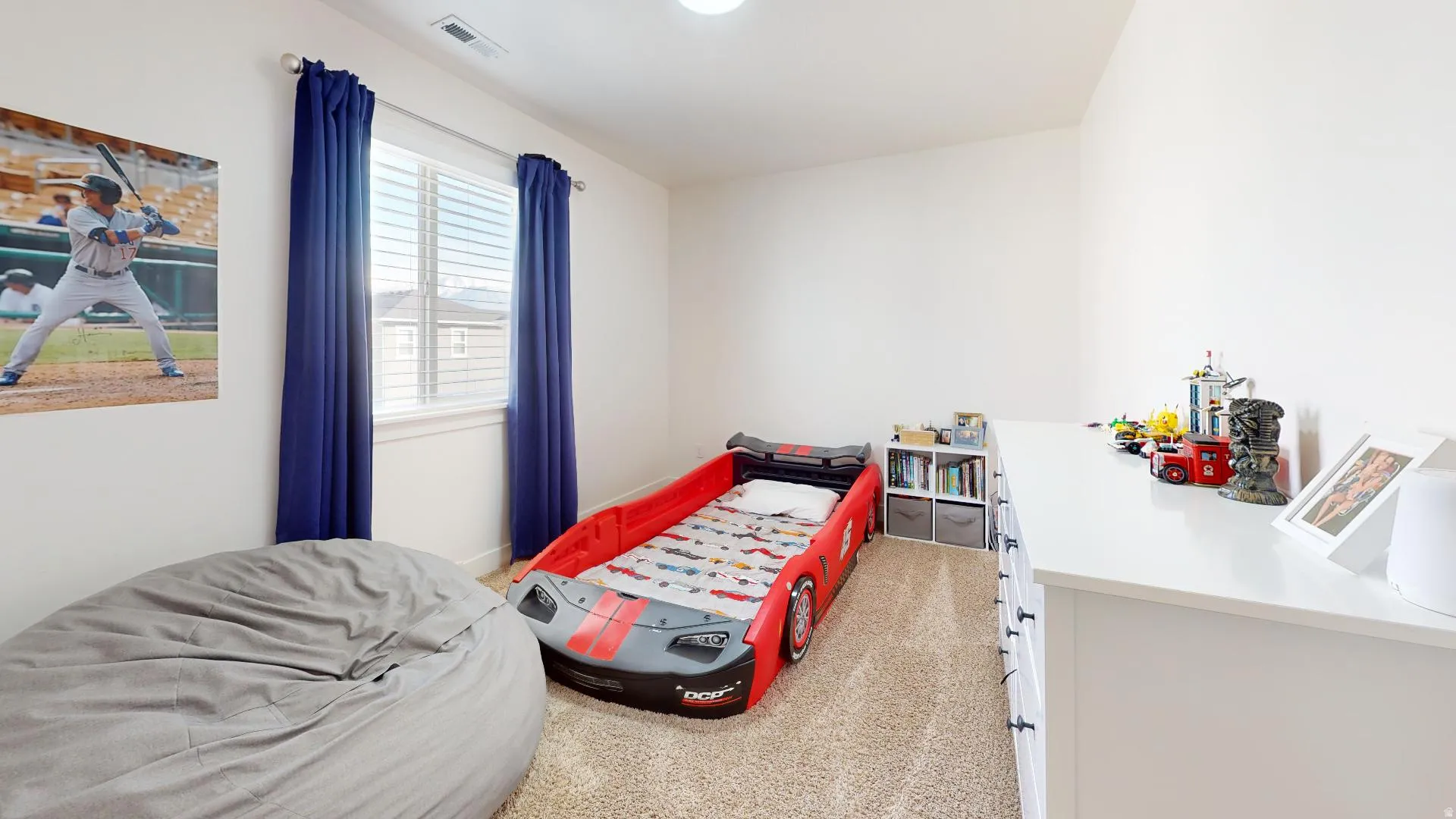 Bright room featuring light-toned carpeting, a window with horizontal blinds and drapery, and white walls