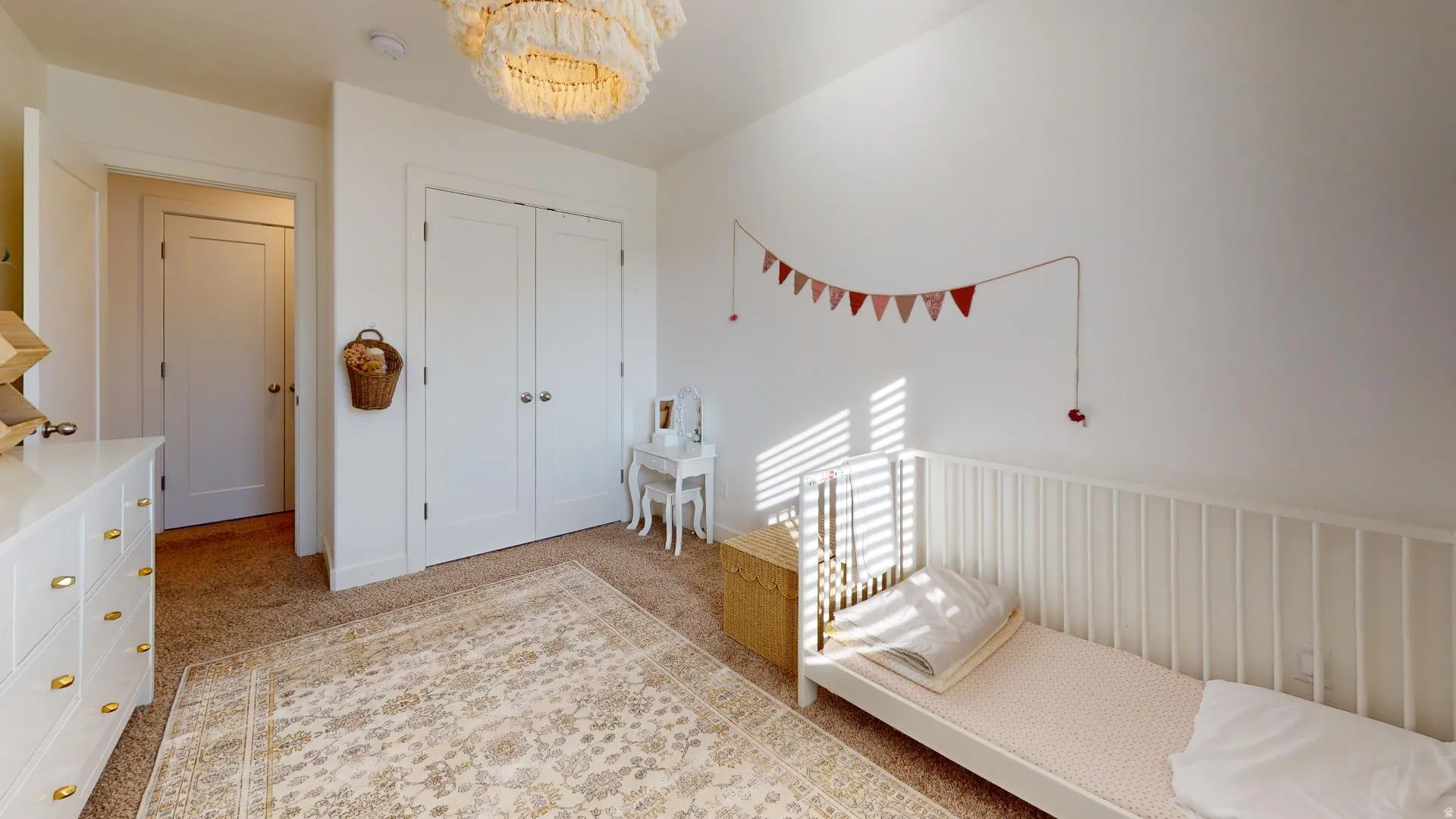 Plush carpet flooring, white walls, and a prominent chandelier
