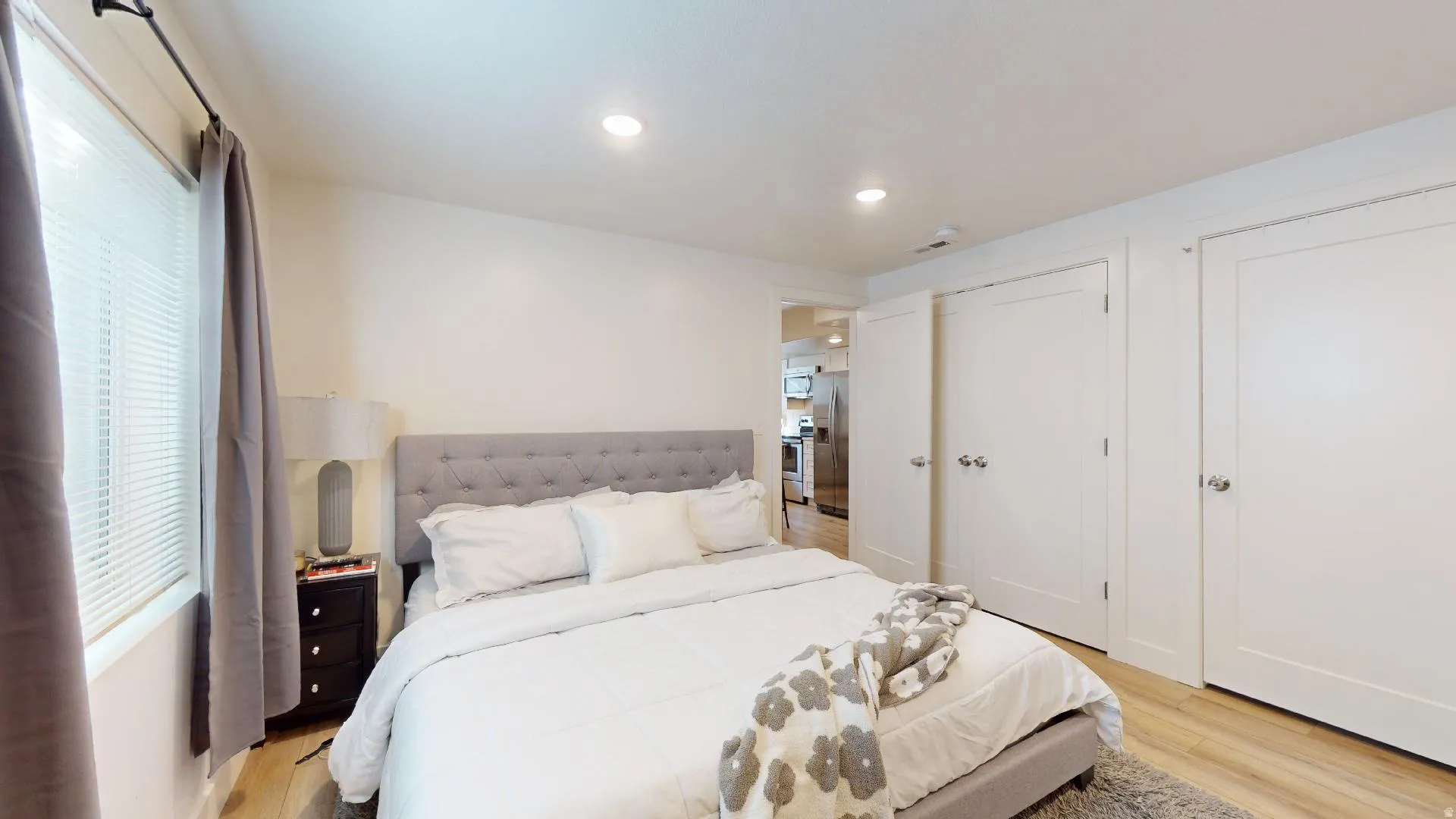 Wood-finish flooring, recessed lighting, white interior doors, window with blinds