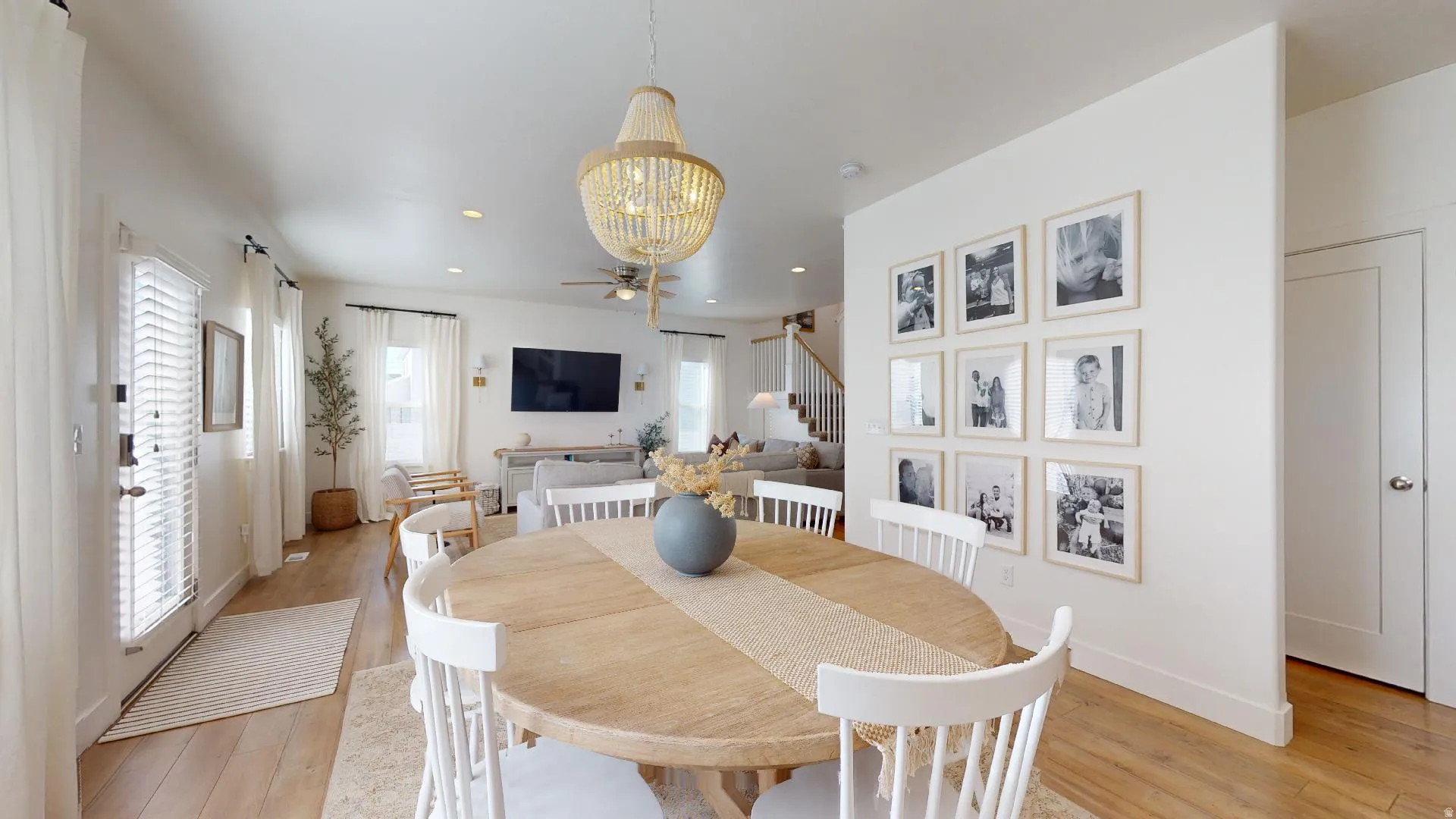 Open-concept living space with wood-finish flooring, a contemporary chandelier, recessed lighting, and a white paneled door