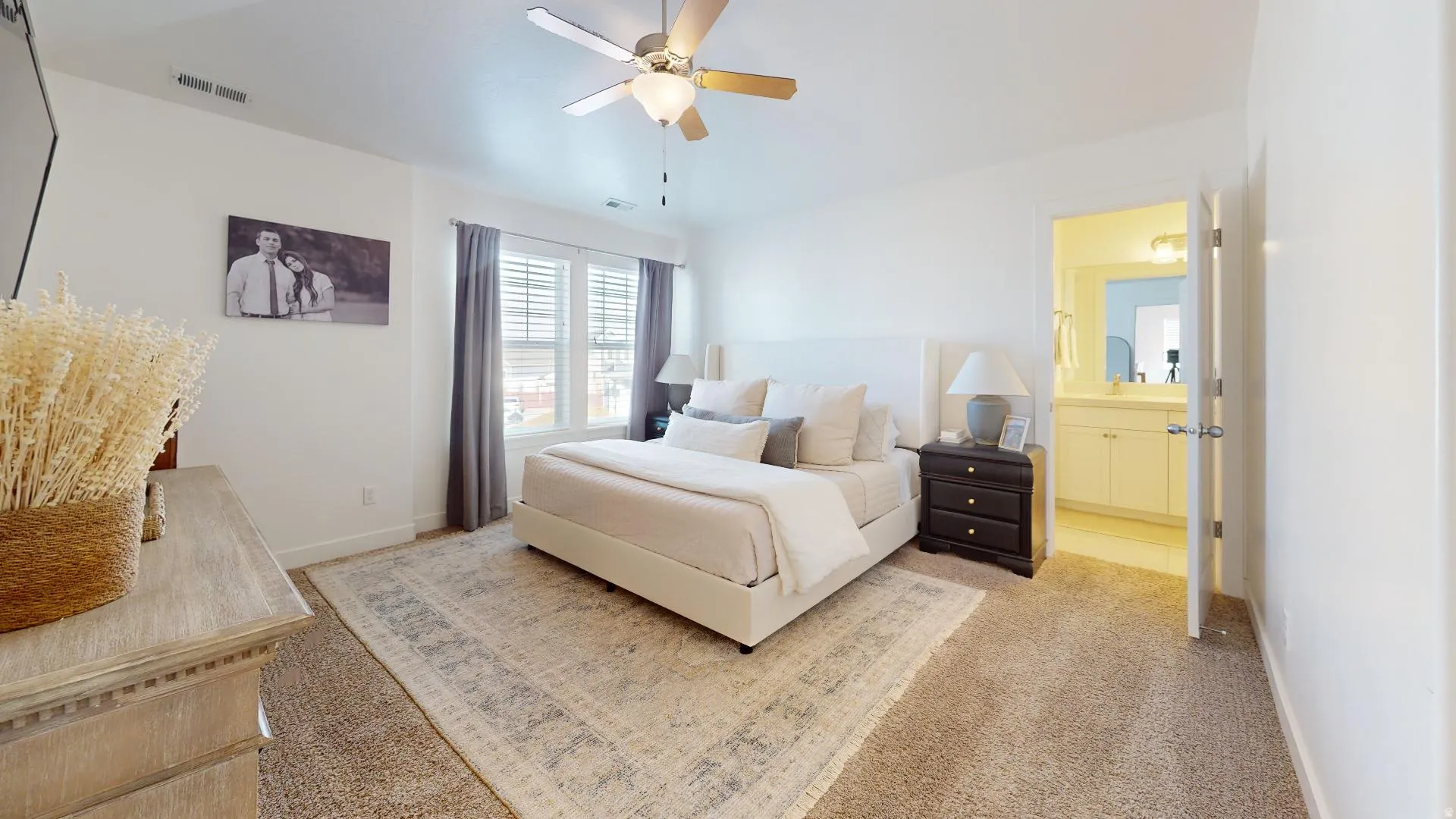 Spacious bedroom featuring carpet flooring, a ceiling fan, and window blinds with drapery