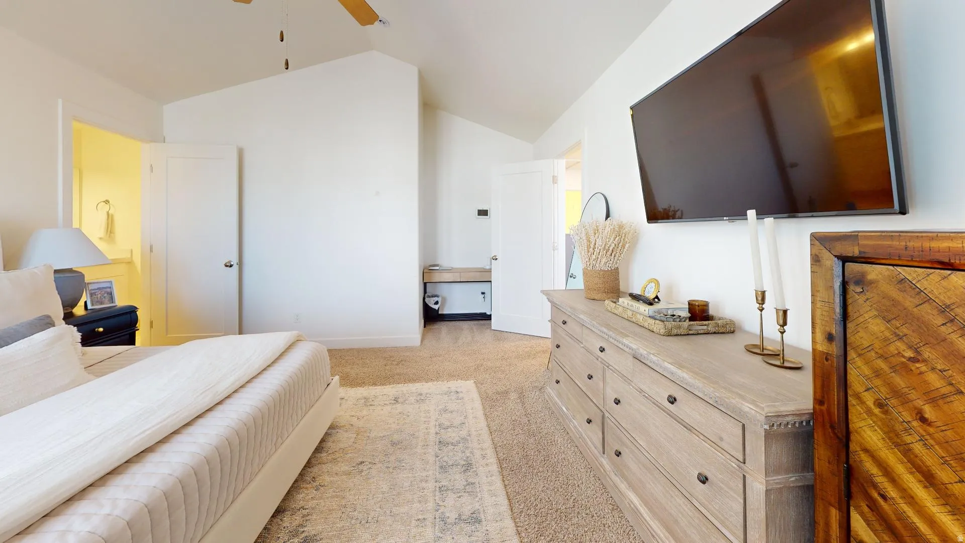 Vaulted ceiling with a ceiling fan, plush carpet, and a built-in vanity area