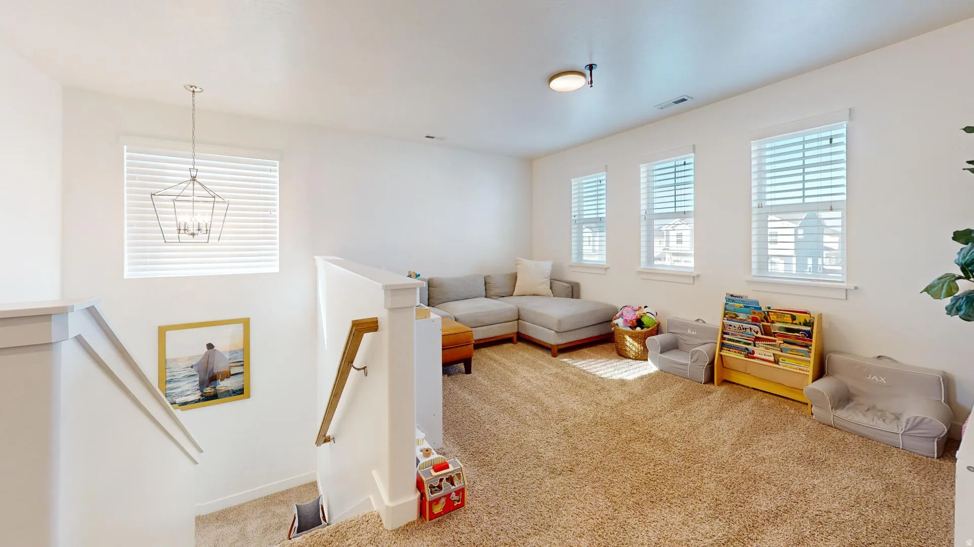 Carpeted upper-level space featuring multiple windows, a ceiling light fixture, and a hanging light fixture