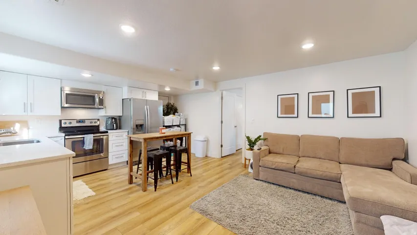 Kitchen featuring stainless steel appliances, white cabinetry, and light-toned wood-finish flooring