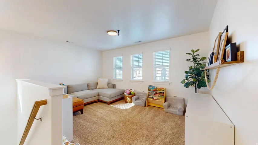 Carpeted loft space with multiple windows and a built-in wall shelf