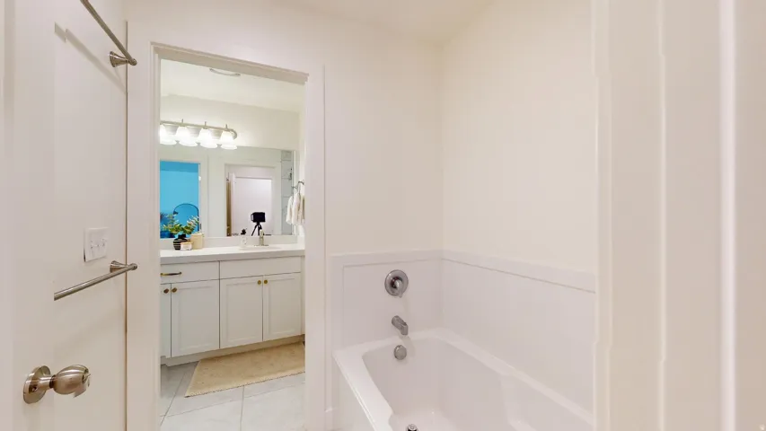 White built-in bathtub with chrome fixtures, white wainscoting, and a neutral wall finish
