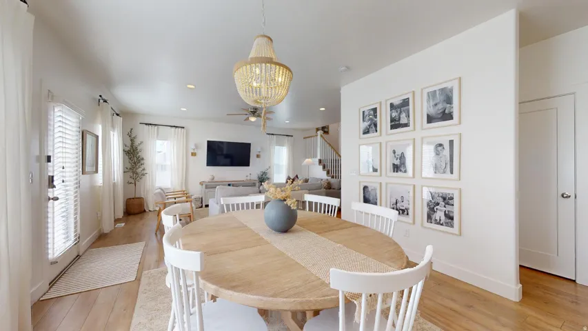 Open-concept living space with wood-finish flooring, a contemporary chandelier, recessed lighting, and a white paneled door