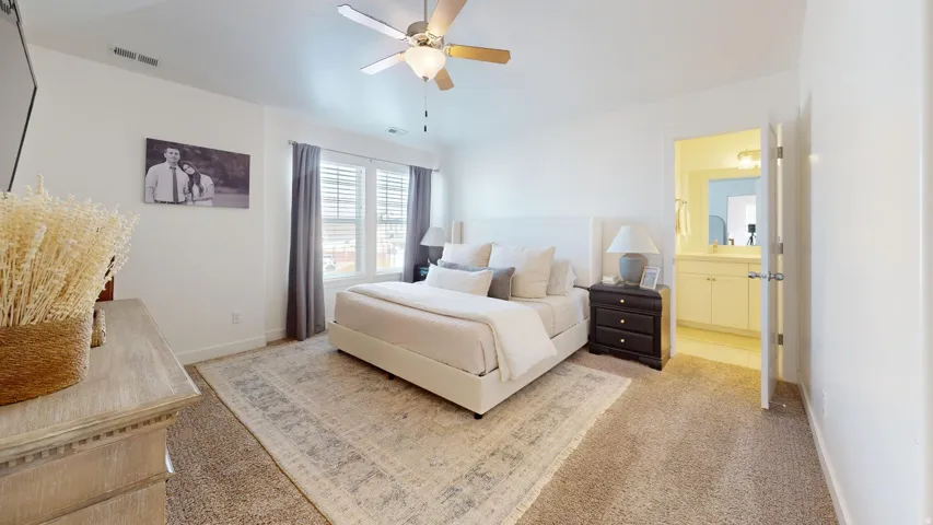 Spacious bedroom featuring carpet flooring, a ceiling fan, and window blinds with drapery