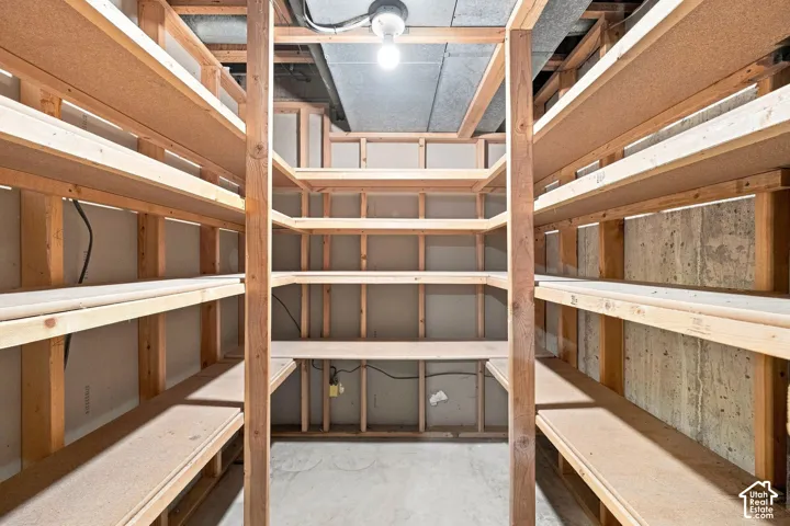 Extensive wood shelving system with exposed framing, concrete flooring, and exposed ceiling joists