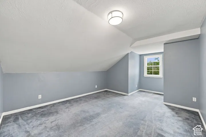 Sloped ceiling with recessed lighting, light blue wall paint, white trim, and gray carpet flooring