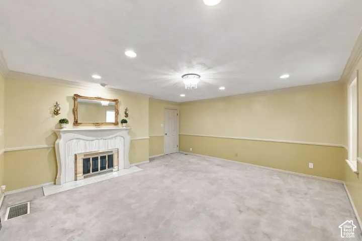 Recessed lighting, crown molding, chandelier, fireplace with decorative mantel, and light carpeting