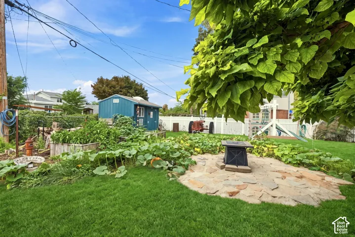 Expansive green lawn with a flagstone patio featuring a propane fire pit