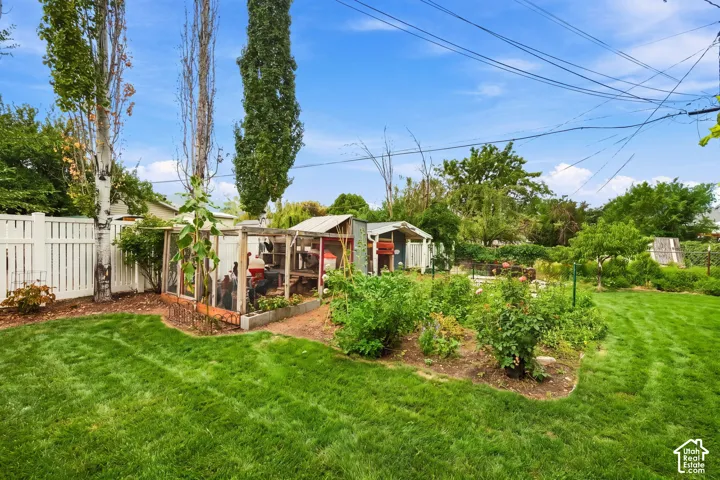 Mature landscaped grounds featuring a lush, manicured lawn with established perimeter plantings, raised garden beds, and a chicken coop.