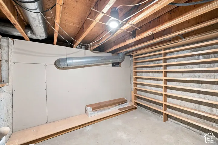 Exposed ceiling joists, concrete flooring, ductwork, and unfinished wall paneling
