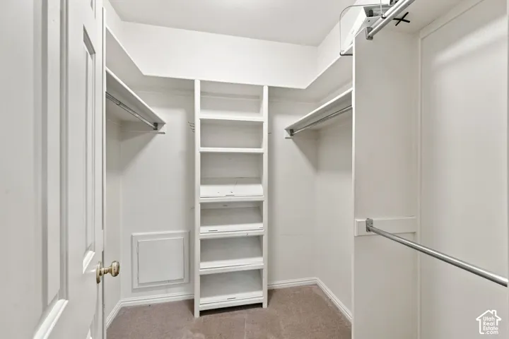 Built-in shelving, multiple hanging rods, and light-toned carpeting