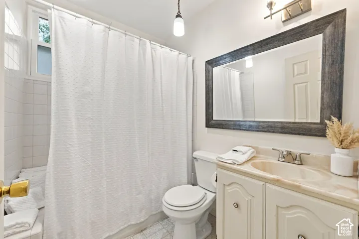 Bathroom featuring a single vanity with an integrated sink, framed mirror, and a tiled shower with a window