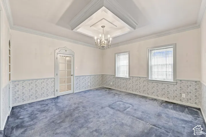 Tray ceiling with a central chandelier, two windows, and a glass-paneled interior door