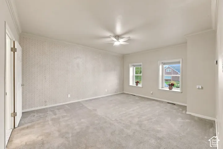 Spacious room with patterned wallpaper, crown molding, and two windows