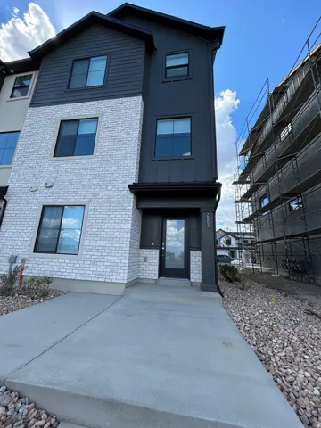 Modern exterior featuring white brick accents, dark vertical siding, and a contrasting dark entry door with glass paneling