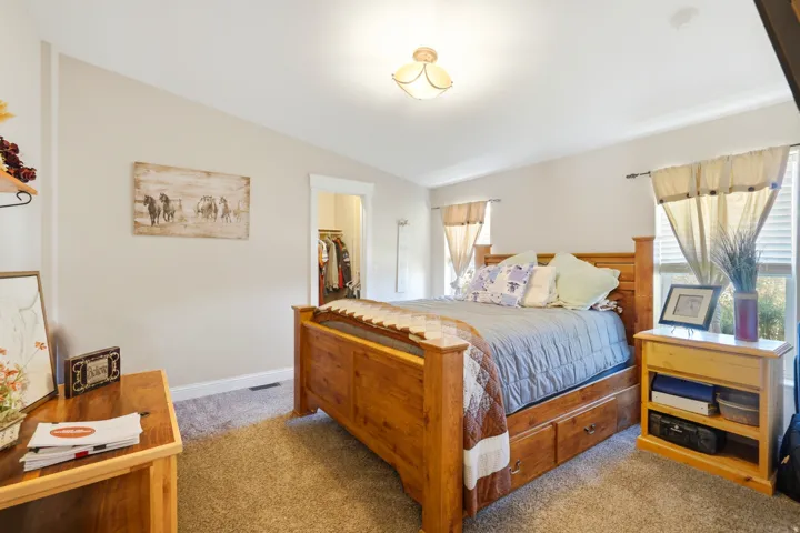 Carpeted bedroom with a built-in closet, neutral wall paint, and multiple windows with blinds