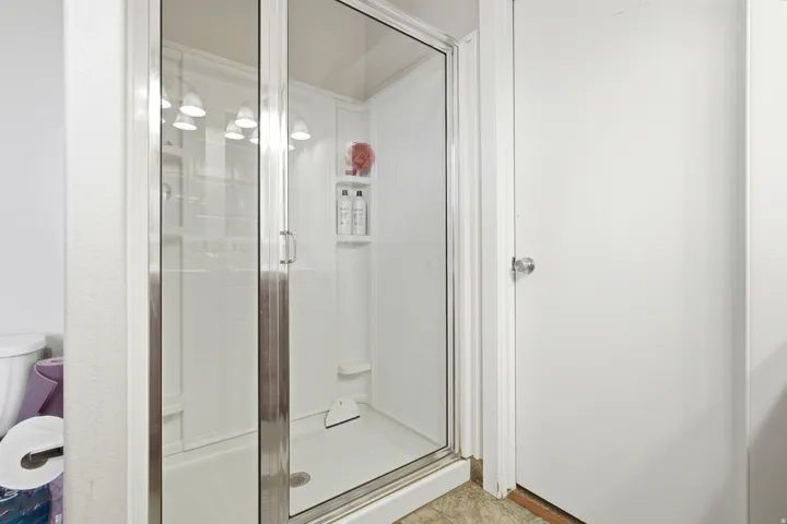 Glass-enclosed shower with a built-in shelf and white tile surround