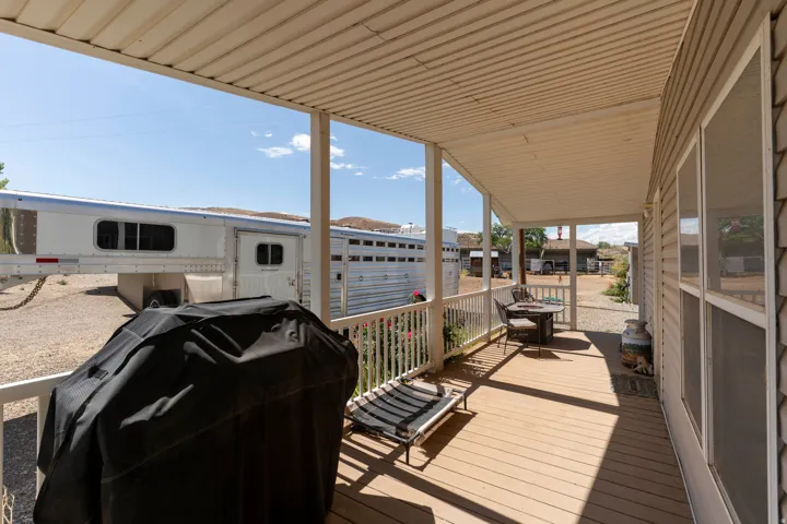Covered porch featuring wood-finish decking, white railings, and a vinyl siding exterior