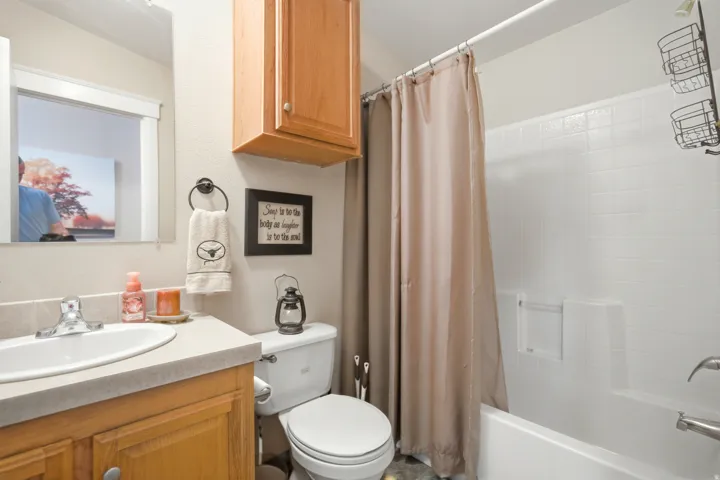 Bathroom featuring a single vanity with a laminate countertop, undermount sink, and wood cabinetry