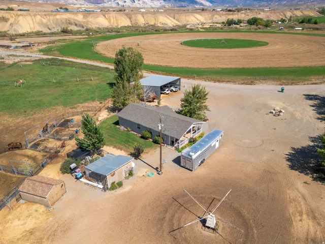 Property featuring a single-story dwelling, multiple outbuildings, fenced enclosures, and expansive open terrain