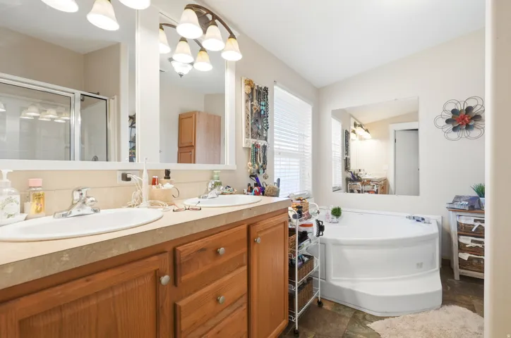 Dual vanity with integrated sinks, wood-finish cabinetry, and overhead lighting