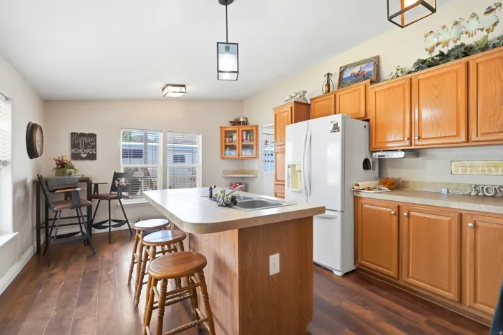 Kitchen featuring a wood-finish floor, light wood cabinetry, laminate countertops, and a double basin sink