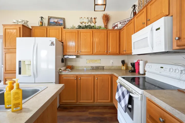 Kitchen featuring wood-finish cabinetry, solid surface countertops, a side-by-side refrigerator, and a built-in microwave