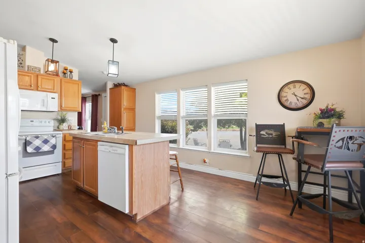 Kitchen featuring a central island with sink, wood-finish flooring, recessed lighting, and multiple windows