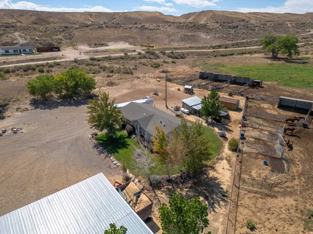 Expansive property with a single-story residence, multiple outbuildings, fenced enclosures, and a large metal-roofed structure