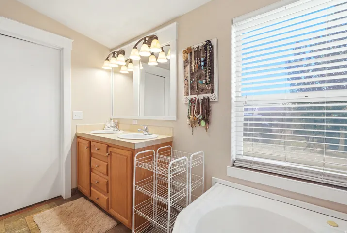 Double vanity with integrated sinks, wood-finish cabinetry, and overhead lighting