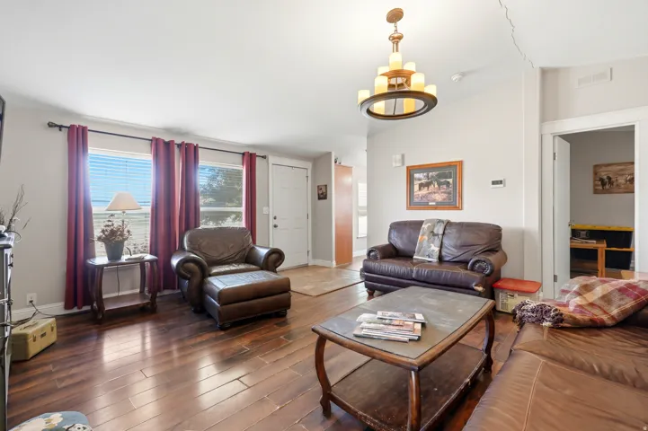 Wood-finish flooring throughout, light neutral wall color, and a multi-tiered chandelier