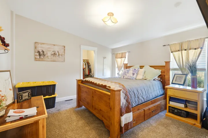 Vaulted ceiling with a flush-mount light fixture, wall-to-wall carpeting, and multiple windows