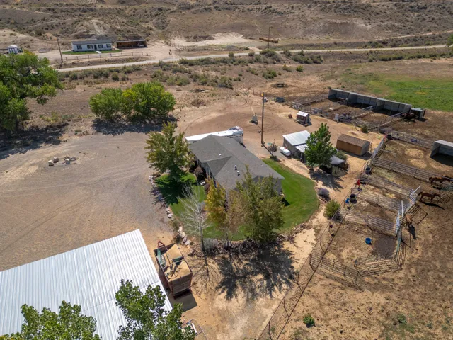 Expansive property featuring a ranch-style home, multiple fenced paddocks, a large metal-roofed barn, and several outbuildings