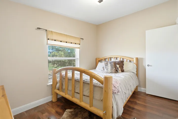 Rich wood-finish flooring, neutral wall paint, and a white door with a polished chrome handle