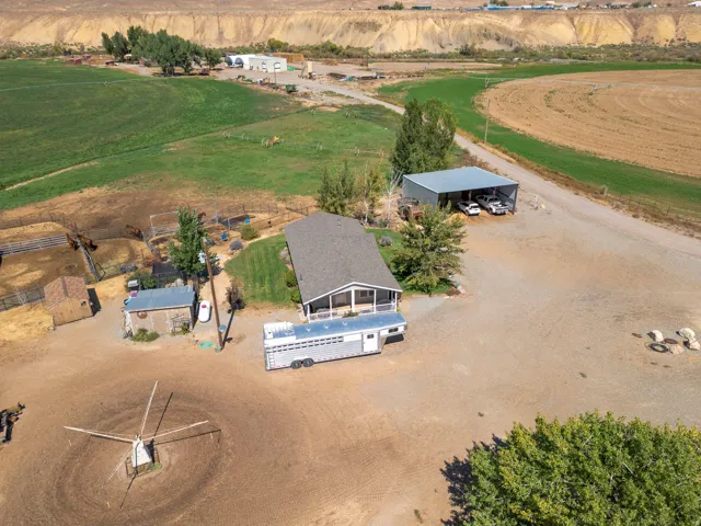 Expansive rural property featuring a main residence, a detached shed, a covered carport, and fenced animal enclosures