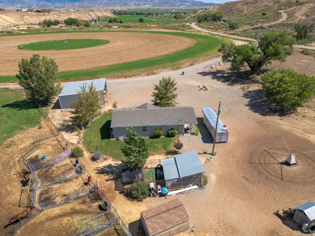 Expansive property with a single-story residence, multiple outbuildings, and fenced corrals