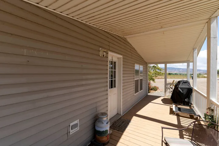 Expansive covered porch featuring a painted wood-finish deck, white railing, and a durable vinyl siding exterior