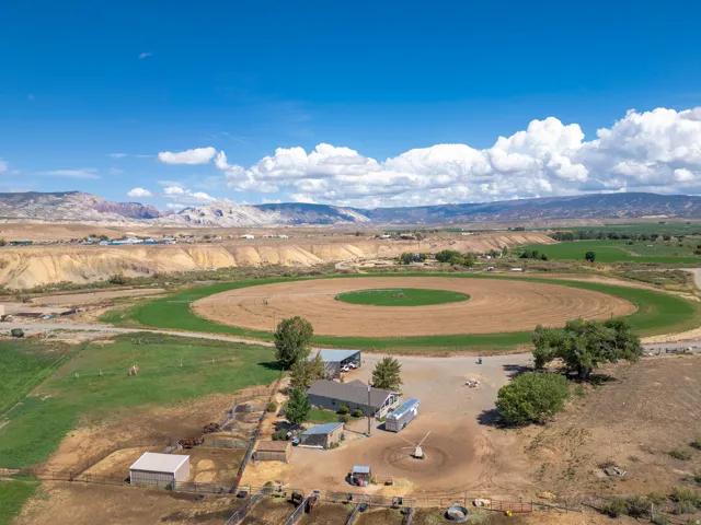 Ranch-style dwelling with surrounding agricultural land, large circular field, and open terrain